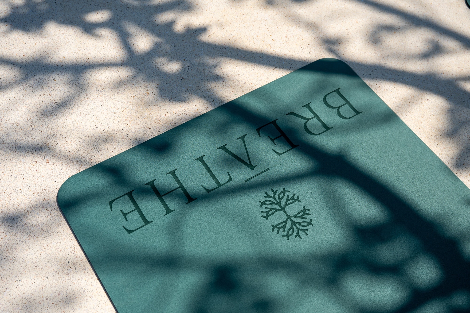 Breathe branded yoga mat with tree logo on poolside deck