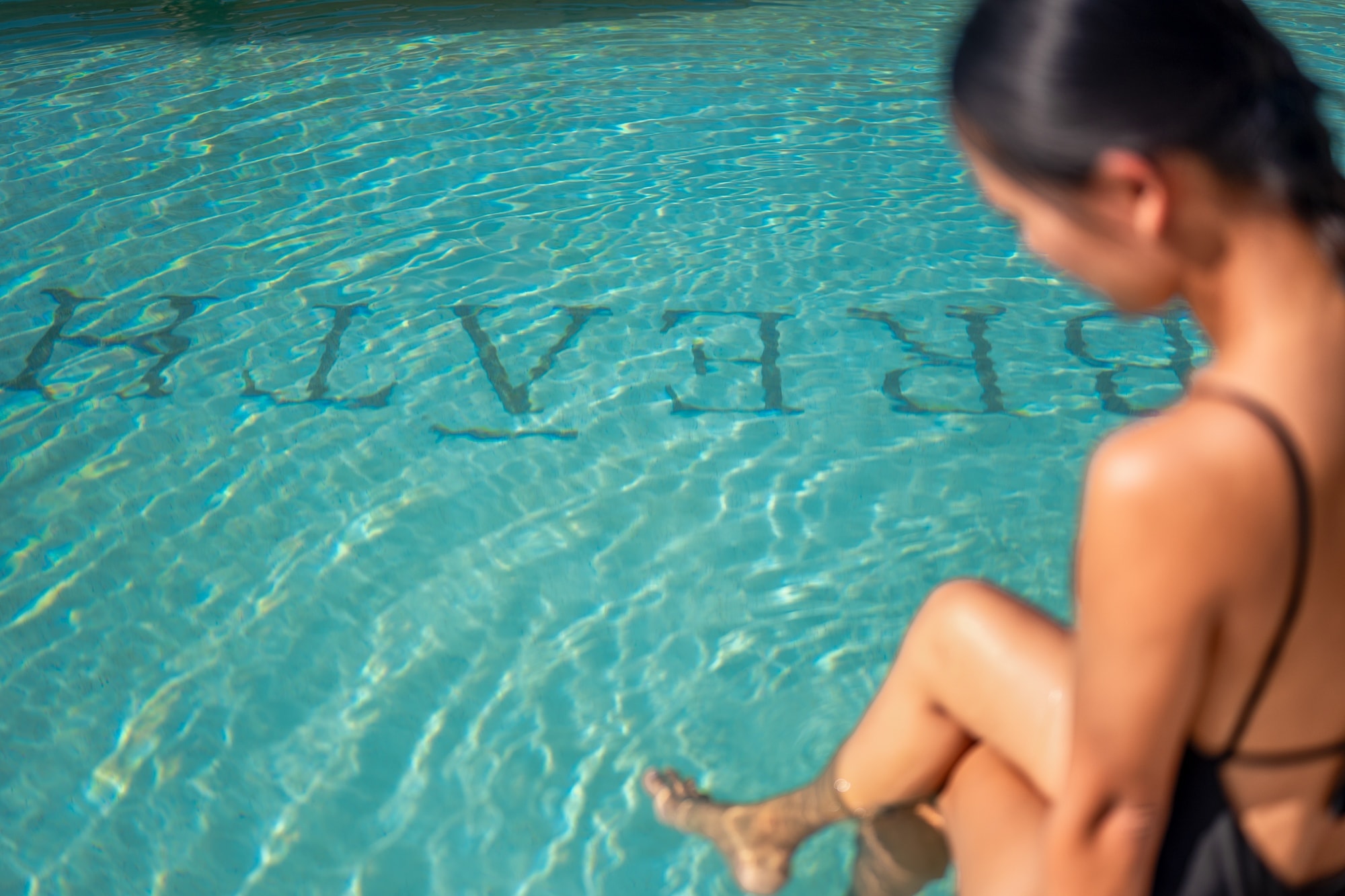 Guest sitting at pool edge with Breathe text visible in the water